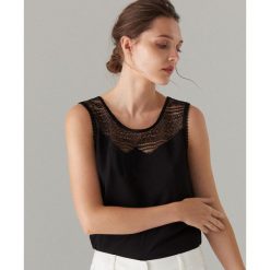 Top z koronkowym zdobieniem - Czarny. Czarne topy damskie Mohito, xl, z aplikacjami, z koronki, bez kołnierzyka. W wyprzedaży za 29,99 zł.
