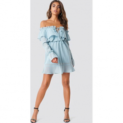 Iva Nikolina x NA-KD Sukienka z odkrytymi ramionami - Blue. Niebieskie sukienki damskie Iva Nikolina x NA-KD, bez wzorów, z poliesteru, z falbankami, bez rękawów, mini, z odkrytymi ramionami. Za 121,95 zł.