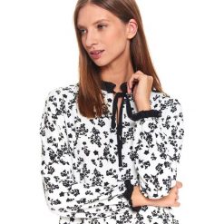 Elegancka koszula w drobny nadruk. Białe bluzki damskie Top Secret, z nadrukiem, z materiału, eleganckie, bez kołnierzyka, bez rękawów. W wyprzedaży za 59,99 zł.