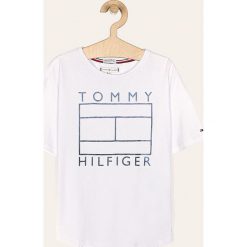 Tommy Hilfiger - T-shirt dziecięcy 128-176 cm. Białe bluzki dziewczęce TOMMY HILFIGER, z nadrukiem, z bawełny, z okrągłym kołnierzem, z krótkim rękawem, krótkie, bez kaptura. W wyprzedaży za 69,90 zł.