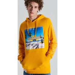 Bluza z fotonadrukiem i napisami - Pomarańczowy. Pomarańczowe bluzy męskie Cropp, s, z napisami, bez kołnierzyka, bez rękawów, bez kaptura. Za 119,99 zł.