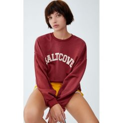 Bluza college z haftowanym napisem. Czerwone bluzy damskie Pull&Bear, z haftami, bez rękawów, bez kaptura. Za 79,90 zł.