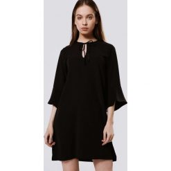 Czarna Sukienka Specified. Czarne sukienki damskie Born2be, s, bez wzorów, z tkaniny, z okrągłym kołnierzem, bez rękawów, mini. Za 49,99 zł.