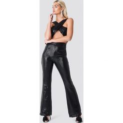 Galore x NA-KD Błyszczący kombinezon z wycięciem - Black. Czarne kombinezony damskie marki Galore x NA-KD, w paski, z poliesteru, bez kołnierzyka, bez rękawów. W wyprzedaży za 64,78 zł.