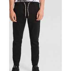 Elastyczne spodnie slim jogger z kieszeniami - Czarny. Czarne spodnie męskie Cropp, m, bez wzorów. W wyprzedaży za 89,99 zł.