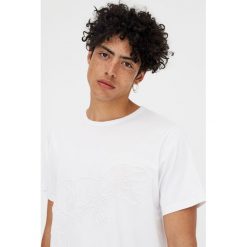 Koszulka z krótkim rękawem i haftowanym dinozaurem. Białe koszulki męskie Pull&Bear, m, z haftami, bez kołnierzyka, z krótkim rękawem, krótkie. Za 41,90 zł.