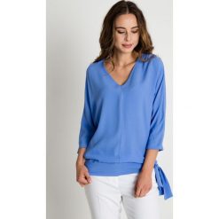 Niebieska bluzka z wiązaniem u boku BIALCON. Niebieskie bluzki damskie BIALCON, uniwersalny, bez wzorów, eleganckie, bez kołnierzyka, bez rękawów. W wyprzedaży za 92,00 zł.