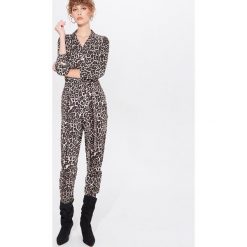 Kombinezon w leopardzie cętki - Beżowy. Brązowe kombinezony damskie Mohito, bez wzorów, bez kołnierzyka, bez rękawów. W wyprzedaży za 39,99 zł.