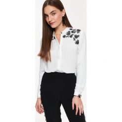 ELEGANCKA KOSZULA Z BŁYSKIEM. Białe koszule damskie marki Top Secret, na zimę, z aplikacjami, eleganckie, ze stójką. W wyprzedaży za 39,99 zł.