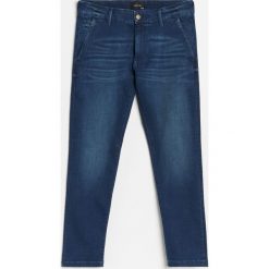 Jeansowe chinosy slim - Granatowy. Niebieskie spodnie męskie Reserved, bez wzorów, z jeansu. Za 129,99 zł.