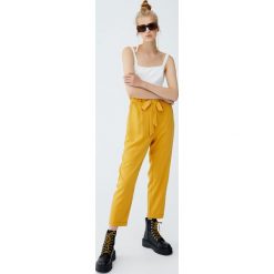 Spodnie paperbag z wiązaniem. Pomarańczowe spodnie damskie Pull&Bear. Za 69,90 zł.