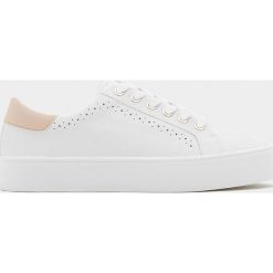 Białe tenisówki z wytłoczeniem i zdobieniem brogue. Białe trampki i tenisówki damskie Pull&Bear, z aplikacjami, bez zapięcia. Za 99,90 zł.
