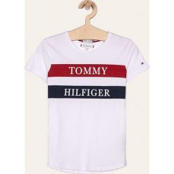 Tommy Hilfiger - T-shirt dziecięcy 128-176 cm. Białe bluzki dziewczęce z nadrukiem, z bawełny, z okrągłym kołnierzem, krótkie. W wyprzedaży za 89,90 zł.
