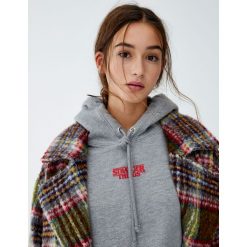 Bluza Netflix Stranger Things Palace Arcade. Szare bluzy damskie Pull&Bear, bez wzorów, bez rękawów, bez kaptura. Za 109,00 zł.