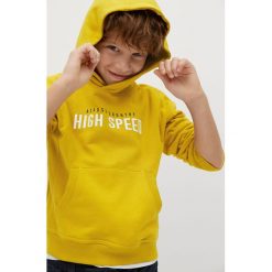 Mango Kids - Bluza bawełniana dziecięca 110-164 cm. Żółte bluzy chłopięce Mango Kids, z nadrukiem, z bawełny, bez rękawów, z kapturem. Za 69,99 zł.