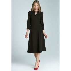 Czarna sukienka z subtelnym pęknięciem na dekolcie i asymetrycznym marszczeniem. Czarne sukienki damskie NIFE, do pracy, s, bez wzorów, z elastanu, eleganckie, z asymetrycznym kołnierzem, bez rękawów, asymetryczne. Za 89,00 zł.