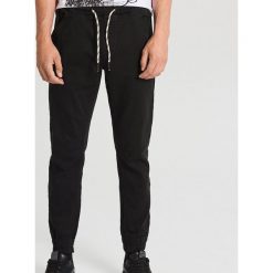 Elastyczne spodnie slim jogger z kieszeniami - Czarny. Czarne spodnie męskie Cropp, m, bez wzorów. Za 129,99 zł.