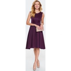 Damska sukienka fit and flare z koronką i wiązaniem na plecach. Fioletowe sukienki damskie Top Secret, na zimę, w koronkowe wzory, z tkaniny, eleganckie, z dekoltem na plecach, bez rękawów, rozkloszowane. W wyprzedaży za 89,99 zł.