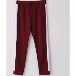 Dresowe spodnie z lampasami ECO AWARE - Bordowy. Czerwone spodnie męskie Cropp, s, bez wzorów, z dresówki. Za 89,99 zł.