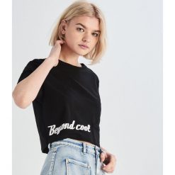 Crop top z napisem - Czarny. Czarne topy damskie marki Sinsay, s, z napisami, bez kołnierzyka. Za 19,99 zł.