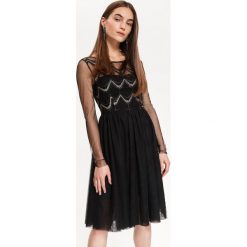 Sukienka damska z koronką, z cekinami. Czarne sukienki damskie Top Secret, w koronkowe wzory, z materiału, eleganckie, bez kołnierzyka, z długim rękawem, długie, rozkloszowane. W wyprzedaży za 119,99 zł.