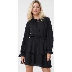 Czarna Sukienka Unique. Czarne sukienki damskie Born2be, s, z aplikacjami, eleganckie, bez kołnierzyka, bez rękawów. Za 149,99 zł.