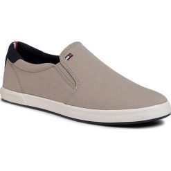 Tenisówki TOMMY HILFIGER - Iconic Slip On Sneaker FM0FM00597 Stone AEP. Brązowe półbuty męskie TOMMY HILFIGER, na co dzień, bez wzorów, z tworzywa sztucznego, bez zapięcia. Za 269,00 zł.