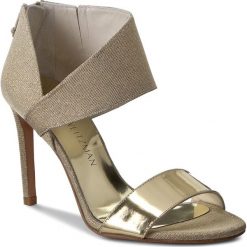 Sandały STUART WEITZMAN - Getonup Pale Gold Nocturn. Żółte klapki damskie marki Stuart Weitzman, bez wzorów, ze skóry ekologicznej, bez obcasa, na obcasie. W wyprzedaży za 999,00 zł.