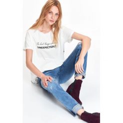 T-shirt damski, z łączonych materiałów, z wydłużonym tyłem, z nadrukiem. Białe t-shirty damskie z nadrukiem, z materiału, eleganckie. W wyprzedaży za 14,99 zł.