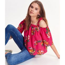 BLUZKA W EGZOTYCZNE KWIATY,Z ODKRYTYMI RAMIONAMI. Różowe bluzki damskie TROLL, xs, w kwiaty, eleganckie, bez kołnierzyka, z krótkim rękawem. W wyprzedaży za 29,99 zł.