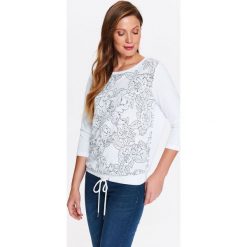 BLUZA NIEROZPINANA DAMSKA, Z BŁYSZCZĄCYM, KWIATOWYM NADRUKIEM Z PRZODU. Białe bluzy damskie Top Secret, na lato, z nadrukiem, bez rękawów, bez kaptura. W wyprzedaży za 49,99 zł.