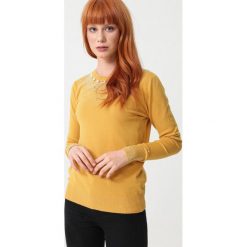 Żółty Sweter Timberglen. Żółte swetry damskie Born2be, xl, z aplikacjami, z dzianiny, eleganckie, bez rękawów, długie, bez kaptura. Za 99,99 zł.