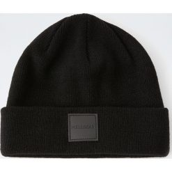 Dzianinowa czapka z gumową naszywką. Czarne czapki męskie Pull&Bear, z aplikacjami, z dzianiny. Za 59,90 zł.