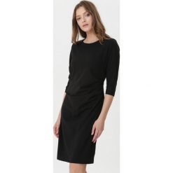 Czarna Sukienka Leandra. Czarne sukienki damskie Born2be, xl, bez wzorów, z okrągłym kołnierzem, bez rękawów, midi, dopasowane. Za 69,99 zł.