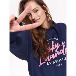 BLUZA NIEROZPINANA DAMSKA Z HAFTEM, Z NADRUKIEM. Czarne bluzy damskie z nadrukiem marki TROLL, na lato, xl, z kapturem. Za 119,99 zł.