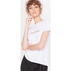 Koszulka z połyskującym napisem Biały. Białe koszulki damskie Mohito, s, z napisami, bez kołnierzyka, bez rękawów. Za 39,99 zł.