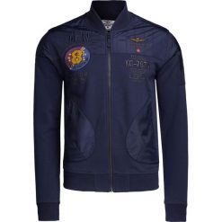 Bluza AERONAUTICA MILITARE. Niebieskie bluzy męskie Aeronautica Militare, z haftami, z bawełny, militarne, ze stójką, bez rękawów, bez kaptura. W wyprzedaży za 812,00 zł.
