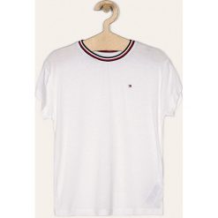 Tommy Hilfiger - T-shirt dziecięcy 128-176 cm. Białe bluzki dziewczęce TOMMY HILFIGER, bez wzorów, z elastanu, z okrągłym kołnierzem, z krótkim rękawem, krótkie, bez kaptura. W wyprzedaży za 129,90 zł.