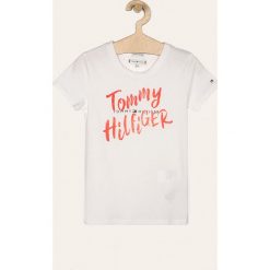Tommy Hilfiger - T-shirt dziecięcy 98-176 cm. Białe bluzki dziewczęce TOMMY HILFIGER, z nadrukiem, z bawełny, z okrągłym kołnierzem, z krótkim rękawem, krótkie, bez kaptura. W wyprzedaży za 79,90 zł.
