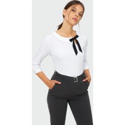 Elegancka bluzka z ozdobnym wiązaniem. Bluzki damskie Greenpoint, bez wzorów, z poliesteru, eleganckie, bez kołnierzyka, bez rękawów. Za 59,99 zł.