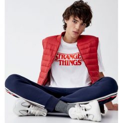 Biała koszulka Netflix Stranger Things z logo. Białe koszulki męskie Pull&Bear, m, bez wzorów, bez kołnierzyka, z krótkim rękawem, krótkie. Za 69,90 zł.