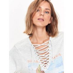 T-shirt krótki rękaw damski, z dekoltem w serek, z wiązaniem, z nadrukiem. Szare t-shirty damskie Top Secret, z nadrukiem, z bawełny, z dekoltem w serek. W wyprzedaży za 19,99 zł.