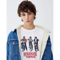 Koszulka Netflix Stranger Things z postaciami na rowerach. Białe koszulki męskie Pull&Bear, m, bez wzorów, bez kołnierzyka, z krótkim rękawem, krótkie. Za 69,90 zł.