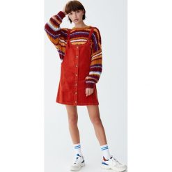 Sztruksowa sukienka ogrodniczka z guzikami z przodu. Szare sukienki z falbanami marki Pull&Bear, ze sztruksu. Za 89,90 zł.