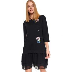SUKIENKA Z OZDOBNYMI APLIKACJAMI. Czarne sukienki damskie Top Secret, na co dzień, na zimę, z nadrukiem, z dzianiny, eleganckie, bez kołnierzyka, bez rękawów. Za 139,99 zł.