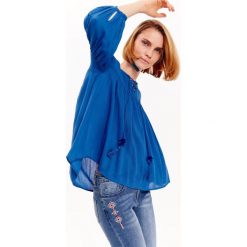 Bluzka damska o luźnym kroju z ozdobnym wiązaniem. Niebieskie bluzki damskie Top Secret, bez wzorów, z tkaniny, eleganckie, z koszulowym kołnierzykiem, bez rękawów. W wyprzedaży za 49,99 zł.
