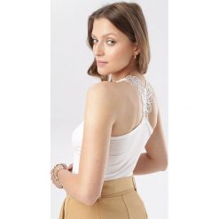 Biały Top Thehaneh. Białe bluzki damskie Born2be, s, bez wzorów, bez kołnierzyka. W wyprzedaży za 19,99 zł.