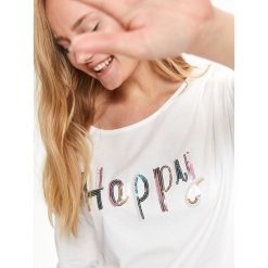 Bluzka dzianinowa z cekinowym napisem happy. Białe bluzki damskie Top Secret, z napisami, z dzianiny, bez kołnierzyka, bez rękawów. Za 49,99 zł.