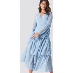 Andrea Hedenstedt x NA-KD Kopertowa sukienka maxi z falbaną - Blue. Niebieskie długie sukienki marki Andrea Hedenstedt x NA-KD, z poliesteru, z kopertowym dekoltem, z długim rękawem, kopertowe. W wyprzedaży za 170,07 zł.