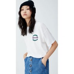 Koszulka w stylu college z napisem na plecach. Szare t-shirty damskie marki Pull&Bear, z napisami, z dekoltem na plecach. Za 59,90 zł.